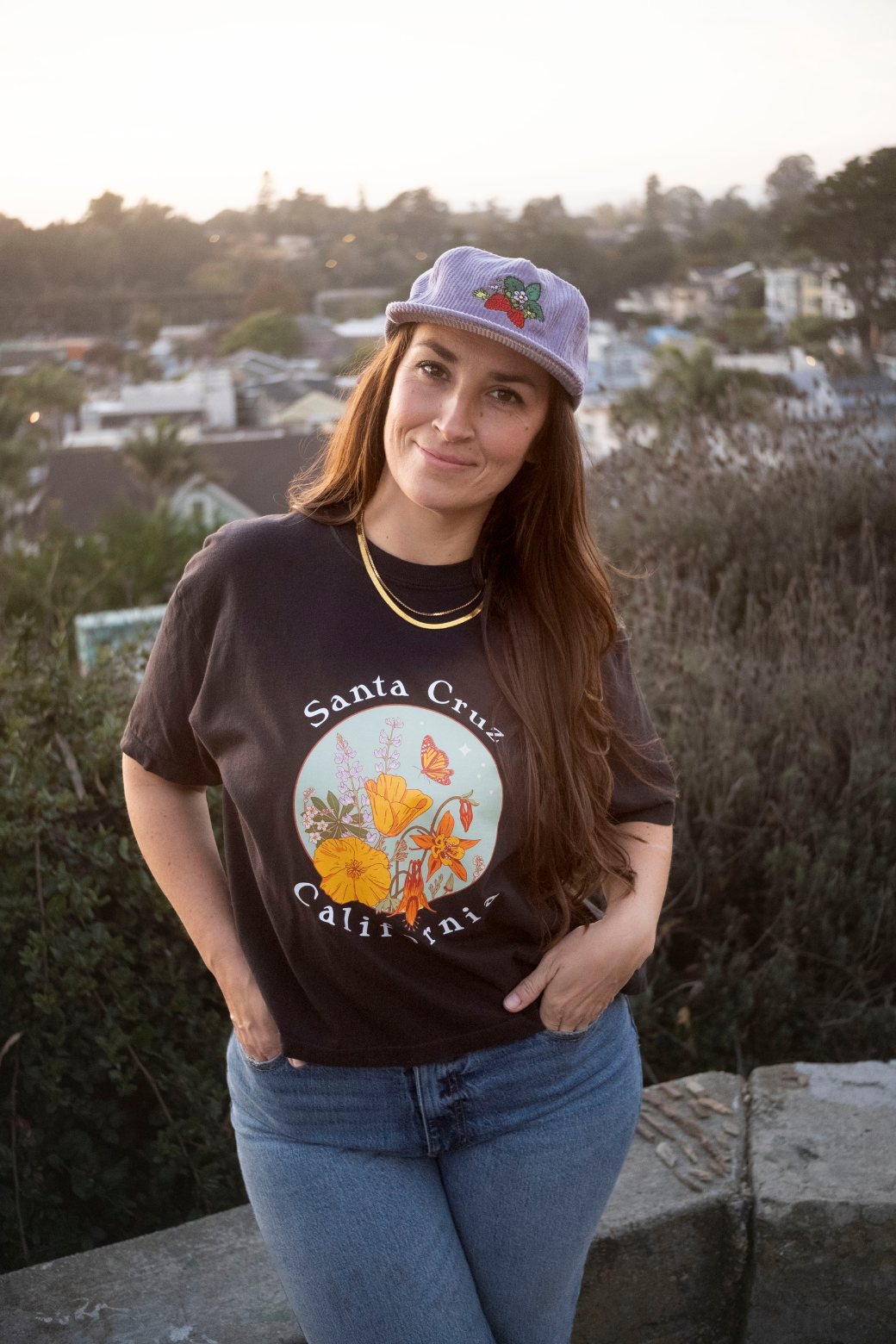 Woman wearing a black 'Santa Cruz' t-shirt with a graphic design, standing outdoors.