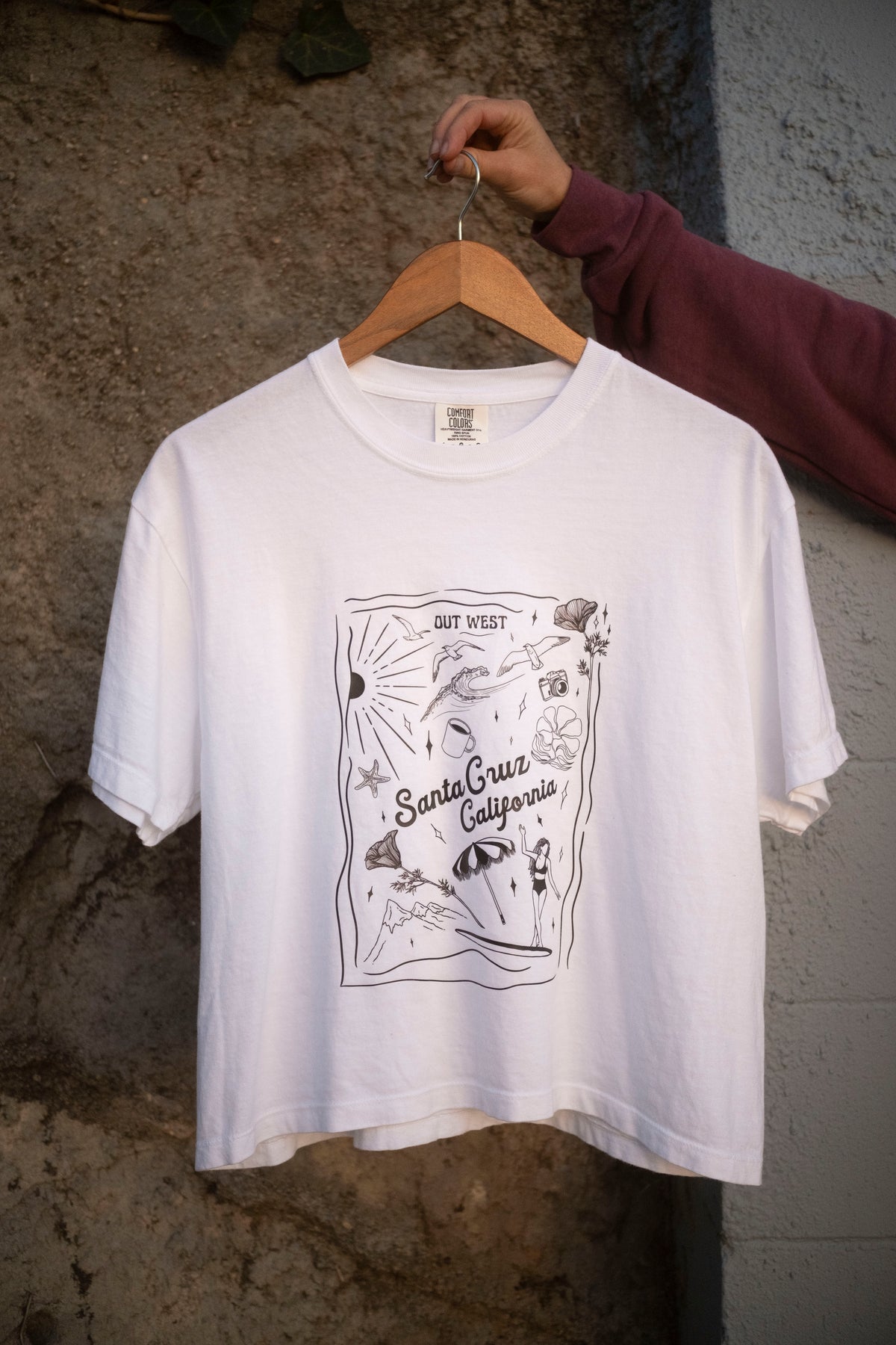 A hand holding up a white t-shirt with Santa Cruz graphics. 