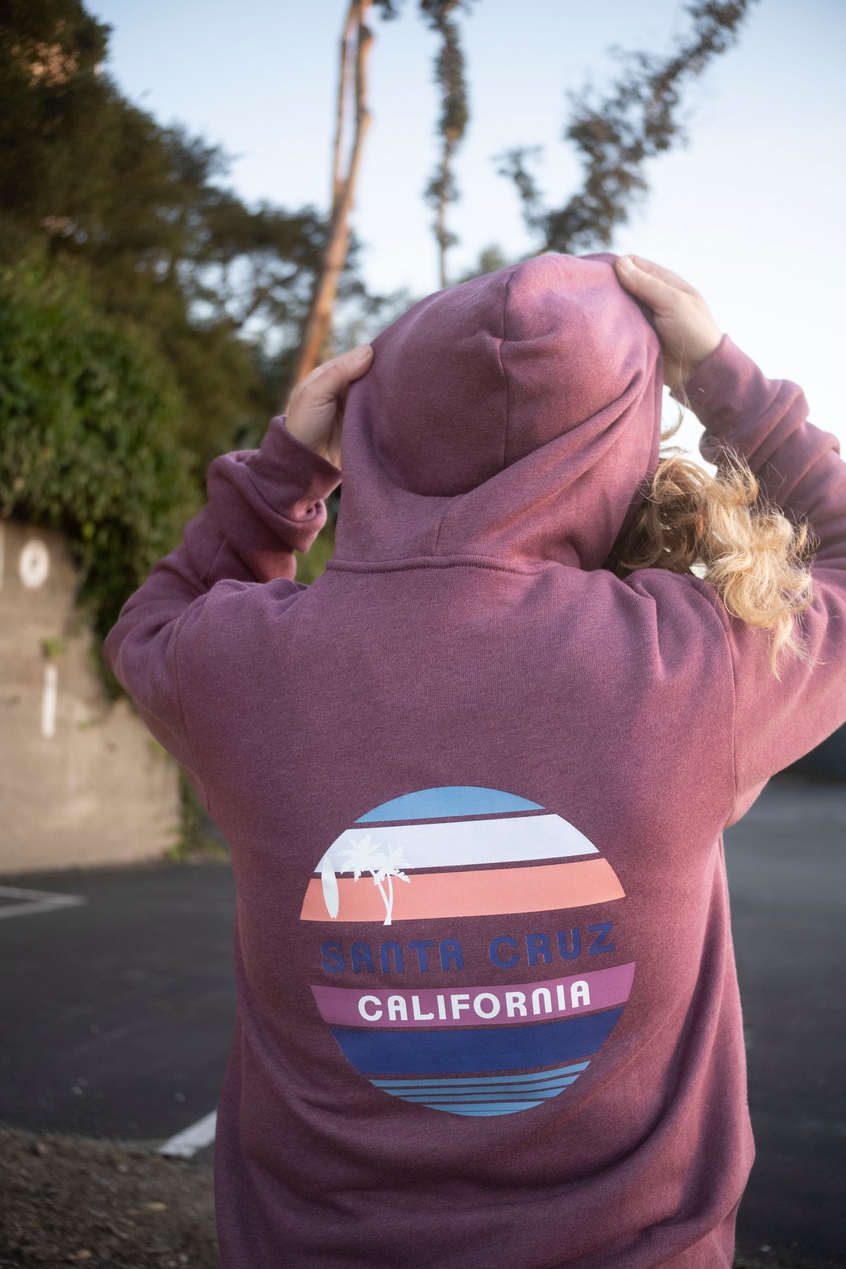 A woman facing away wearing a maroon California hoodie. 
