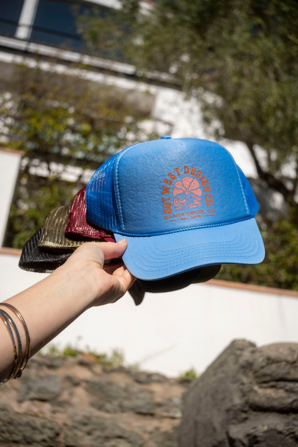 Blue cap with a logo held by a hand outdoors