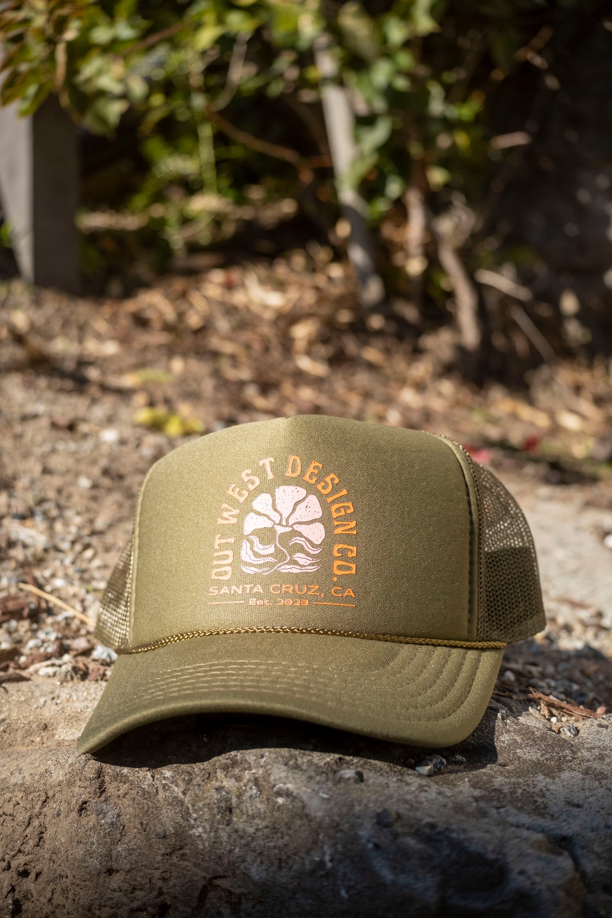 Green cap with mesh back and logo on a rock with natural background