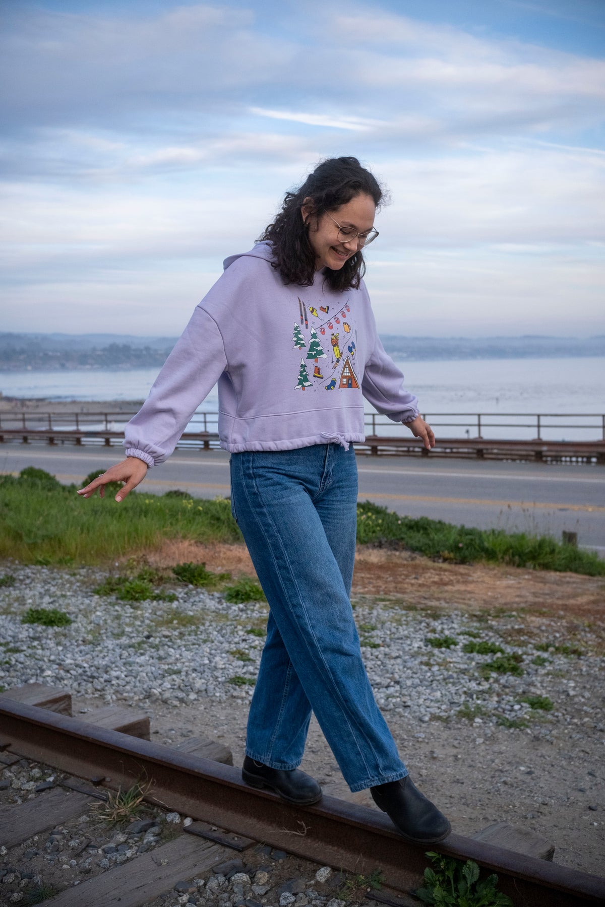 Woman walking on a railway track by a coastal area