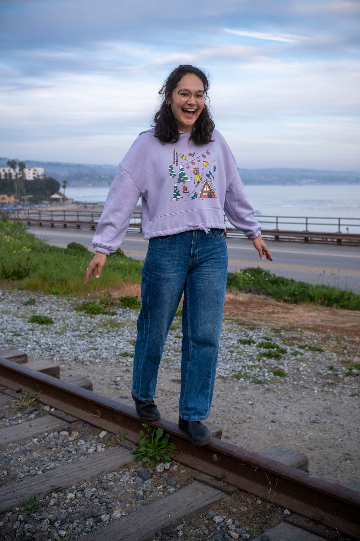 Person standing on train tracks by a scenic waterfront
