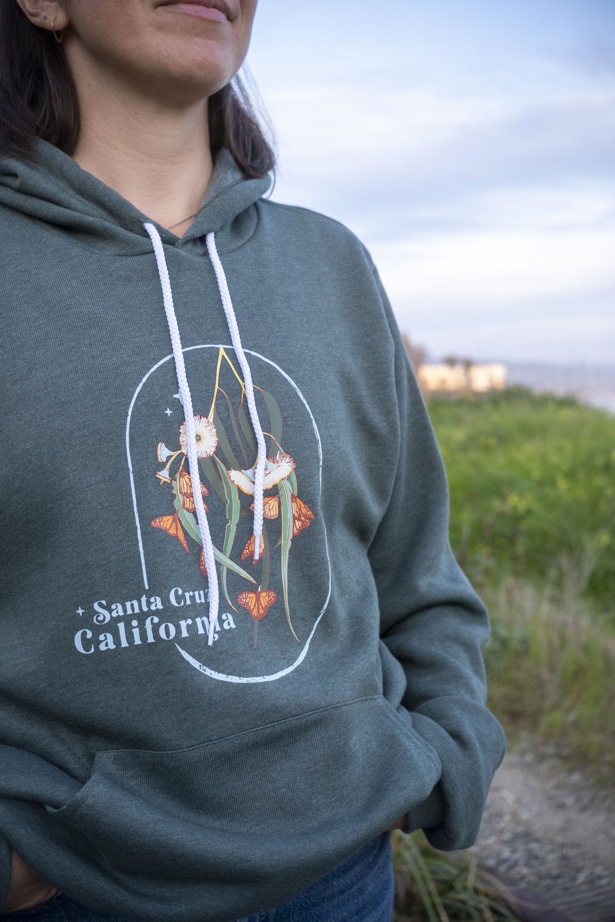 Person wearing a hoodie with a graphic design and text, standing outdoors.