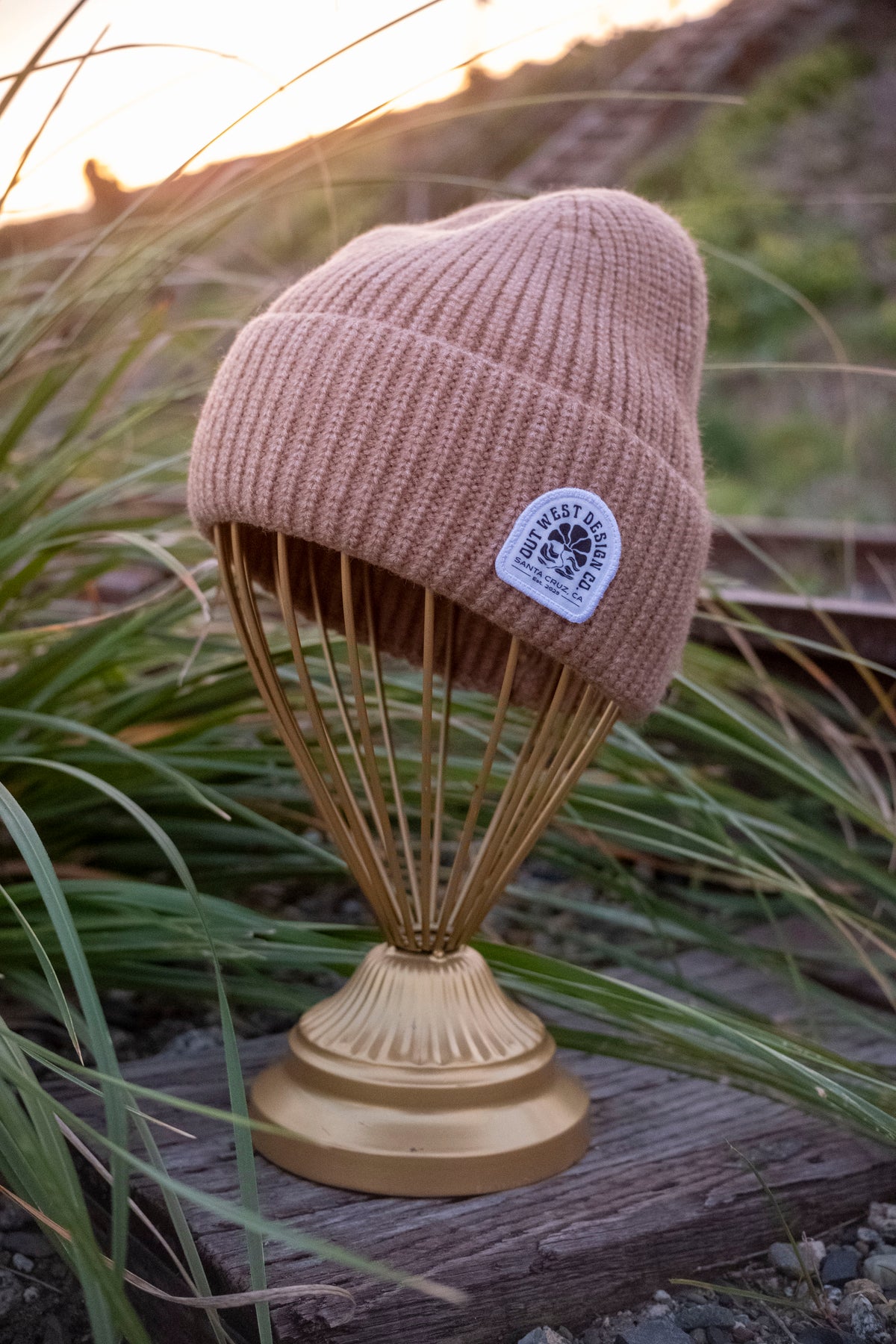 Beige knit beanie on a decorative stand with a natural background