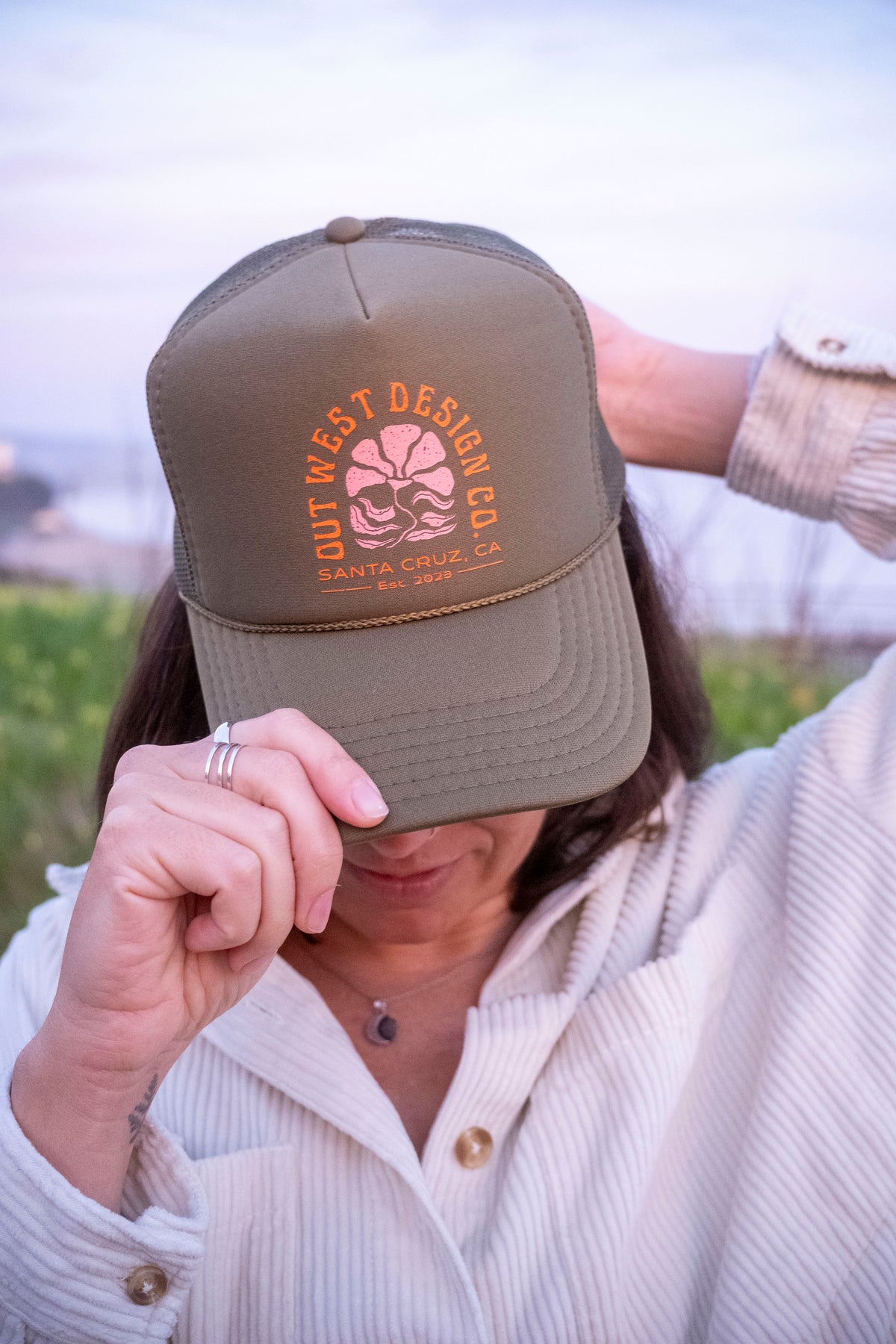 Person wearing a green cap with a logo, standing outdoors.