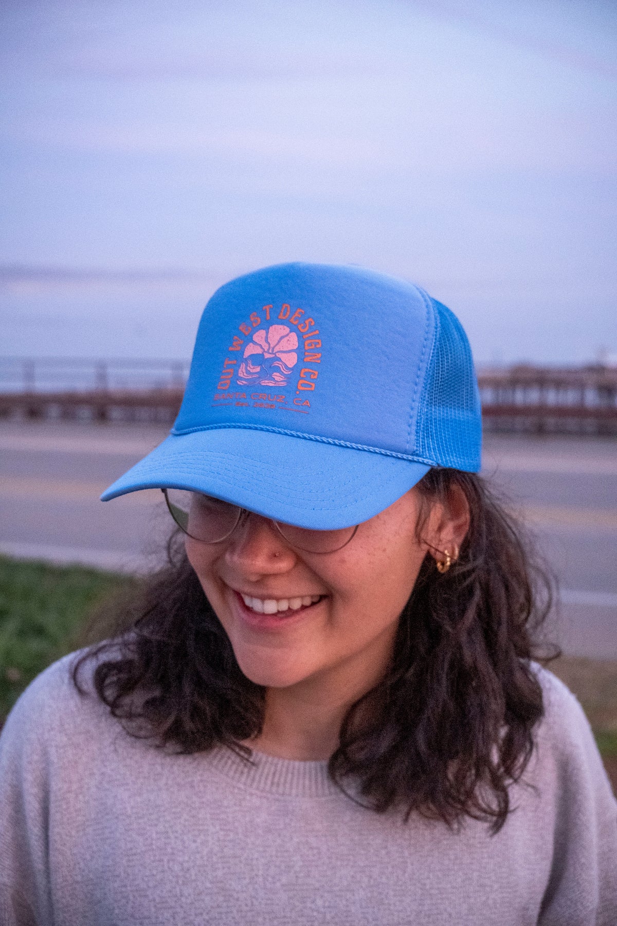 Person wearing a blue cap with a logo, standing outdoors.