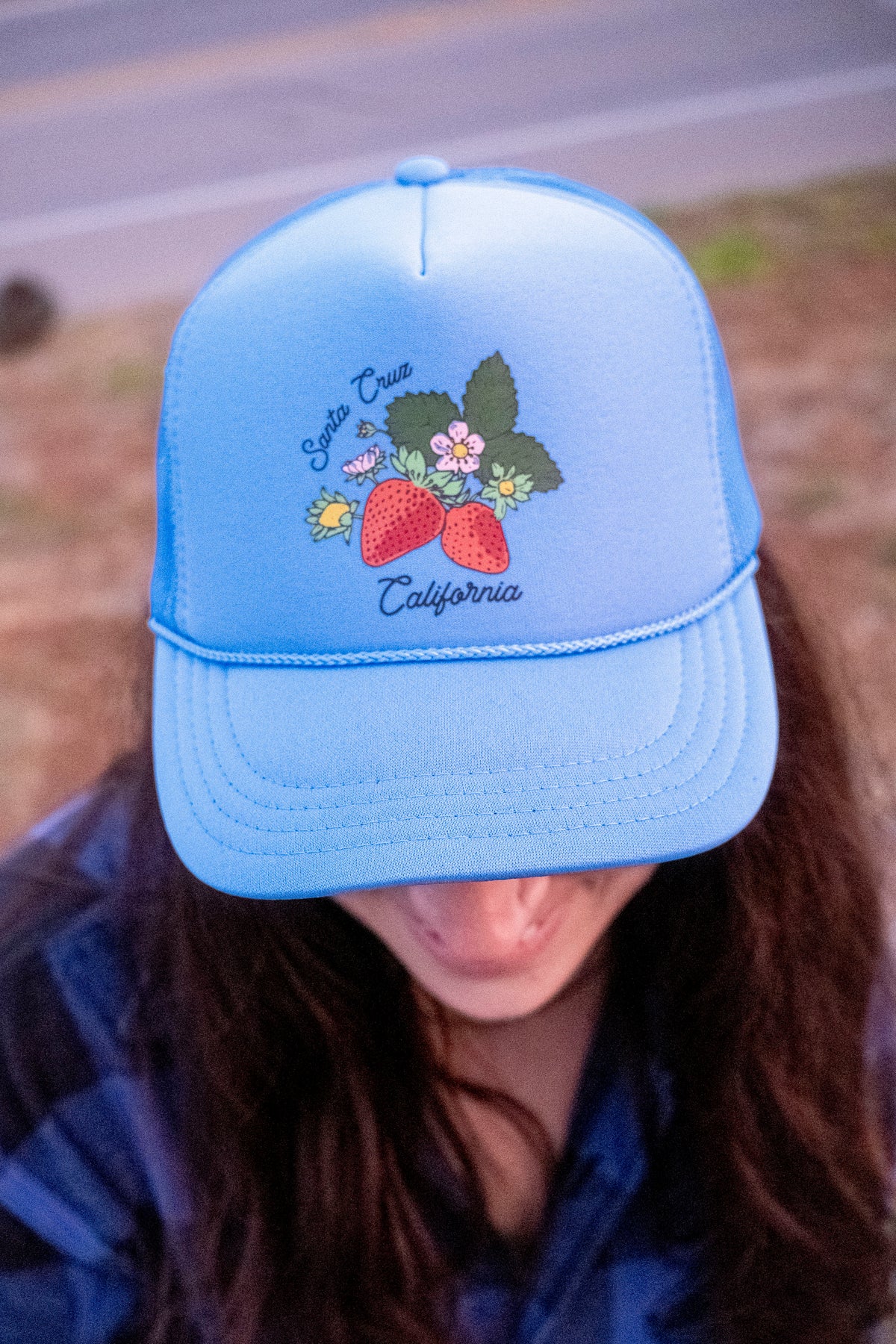 A woman wearing a blue hat with strawberry print. 