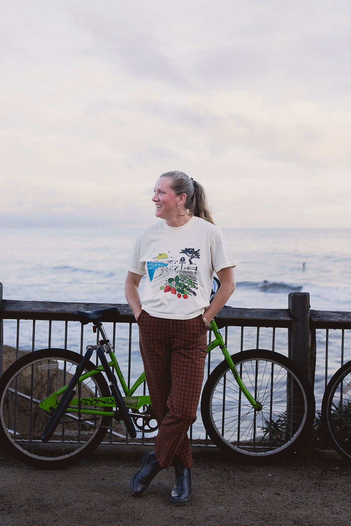 Person standing with a bicycle by a railing overlooking a scenic view.