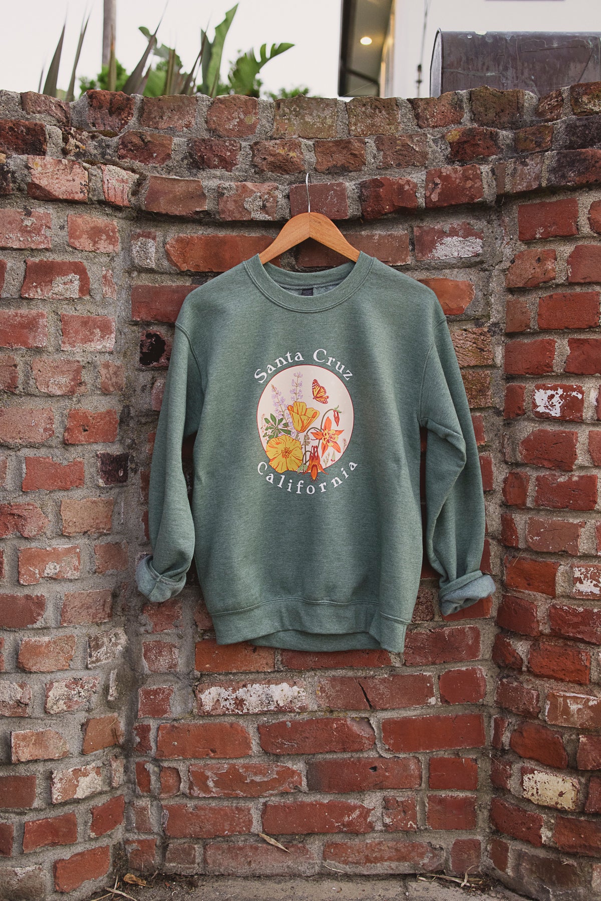 A green sweatshirt hanging against a brick background. 